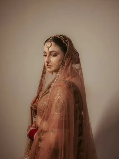 A moody and soulful portrait of the bride, Raghavi, under her veil. The soft lighting and her contemplative expression create a deeply emotional and artistic image.