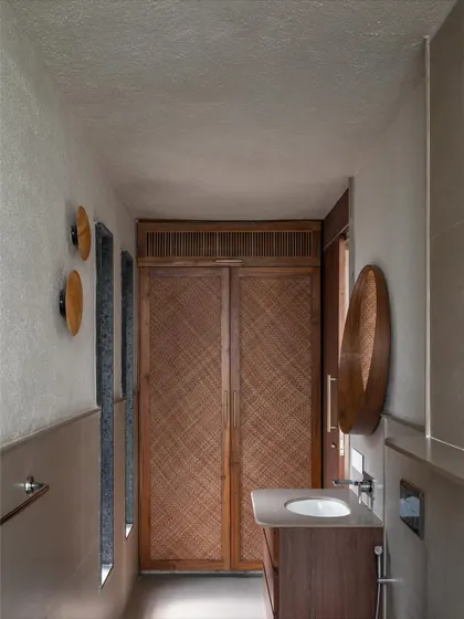 A bathroom in Grove House, featuring woven wood cabinet doors and a simple, elegant vanity.