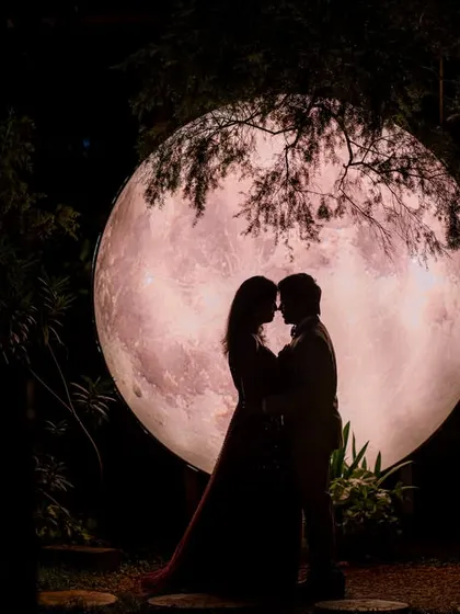 A romantic silhouette of a couple in front of a giant moon prop. This creates a dramatic and timeless image that is all about their connection.