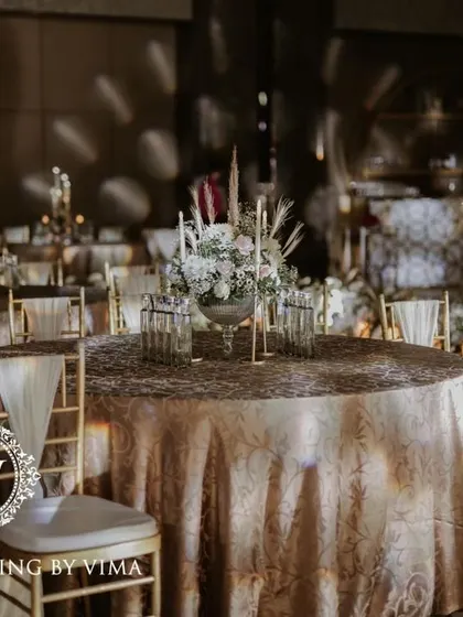 A classic and elegant reception setup symbolizing everlasting love. The stage features a modern, minimalist backdrop with custom monograms, floral arrangements, and soft lighting.