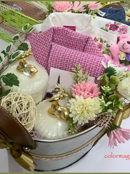 A luxurious baby girl hamper presented in a rustic-chic metal tub. The arrangement includes a pink tweed jacket, a soft teddy bear, and decorative golden deer figures, blending elegance with playful charm.