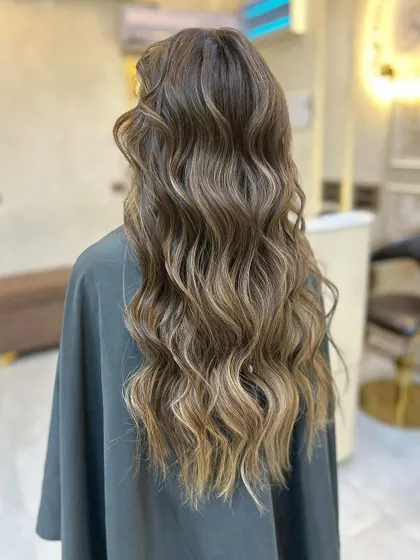 The light catching the waves of this olive ashy brown balayage, showing off the beautiful, multi-dimensional colour.