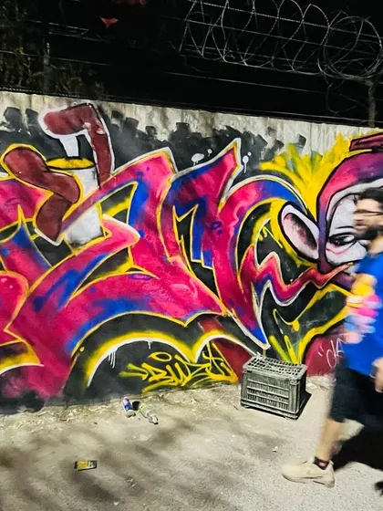 A motion-blur shot of a crew member walking past a freshly painted piece, capturing the energy of a graffiti session.