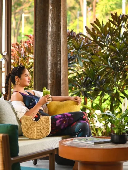 A guest relaxes in our lounge area, surrounded by lush plants and open-air architecture. Every space is designed to be a comfortable nook for reading, sipping a drink, or simply enjoying the view.