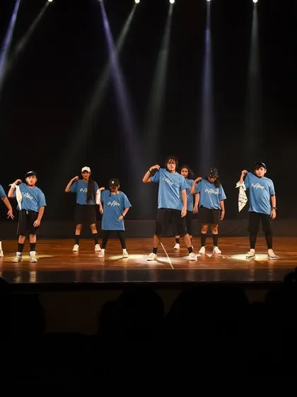 The hip hop crew taking over the stage at Kamani Auditorium, with spotlights highlighting their sharp formations.