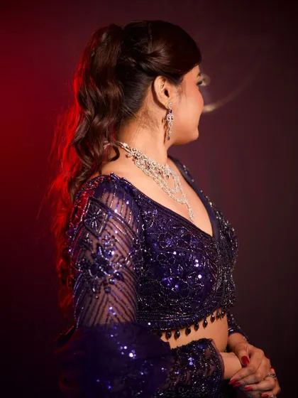 A side profile showing the elegant V-neckline and the sheer, sequined sleeves of the blouse.