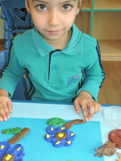 A student carefully crafts flowers from clay during our 'Clayazy' competition, focusing on details and bringing her artistic vision to life.