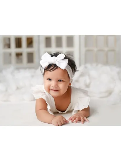 A sweet tummy-time pose from the baby in the all-white setup.