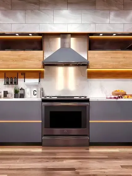 This modern kitchen features handle-less grey cabinets with a thin gold accent line for a touch of elegance. We used wood for the open shelving and integrated warm lighting to create a sophisticated and inviting atmosphere.