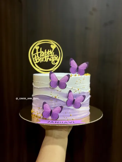 A hand-held shot of the purple ombre butterfly cake, personalized for Janhavi.