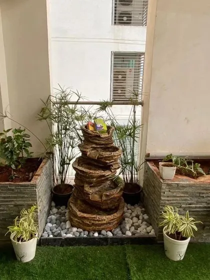 This tiered, rock-like fountain is a perfect addition to a balcony garden. Nestled among planters and set on a bed of white pebbles, it brings the relaxing sound of flowing water to a compact urban space.