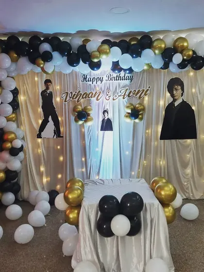 A stylish black, white, and gold themed birthday party for twins Vihaan and Avni. This setup features a full balloon arch and a custom backdrop, creating an elegant and fun atmosphere for the celebration.