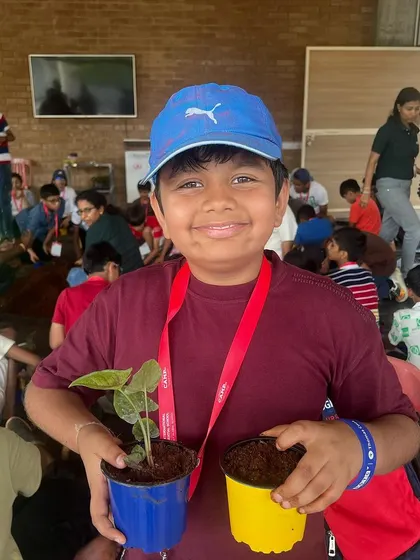 A proud camper shows off the plants he potted during our Summer Camp. Every child gets to take a piece of their experience home with them.