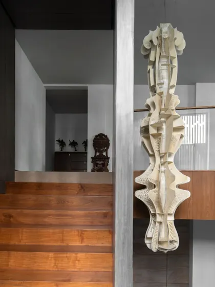 A delicate kirigami installation crafted from parchment leather, titled 'Anugraha'. Positioned near a staircase, its quiet and textural form adds a layer of tactility to a space designed for movement and reflection.