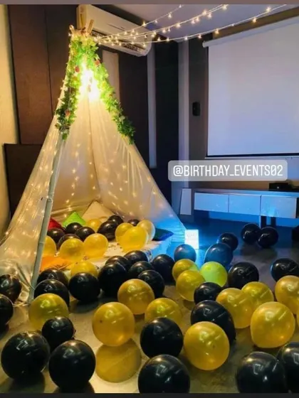 A cozy movie night birthday theme. This setup includes a canopy tent filled with balloons and a projector screen for a private cinema experience.