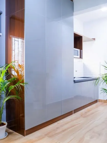 This photo shows the entryway and kitchenette area of a co-living room. The design features sleek, handleless cabinetry and durable laminate finishes, reflecting our focus on creating practical and low-maintenance interiors for shared living environments.
