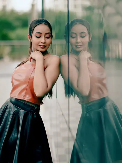 A fashion portrait using reflections to create depth. The model's pose against the glass wall adds a layer of sophistication and modernity to the shot.