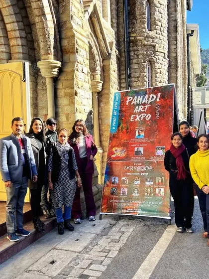 I'm with fellow artists outside PAHADI ART EXPO 2022 at Gaiety Theatre, Shimla, beside the exhibition banner.
