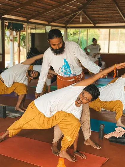 I believe in guiding each student personally. Here, I am offering a gentle adjustment in a forward fold, helping the student to find space and release tension safely. My approach is to meet you where you are, with patience and support, so you can trust your body and deepen your practice without force.