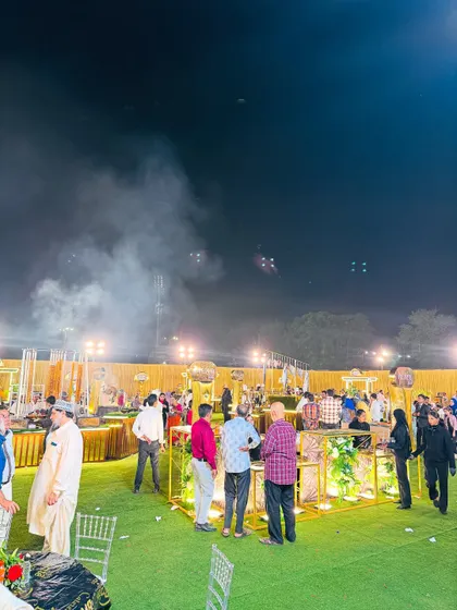 Guests mingling and enjoying food from various stations at a large evening event.
