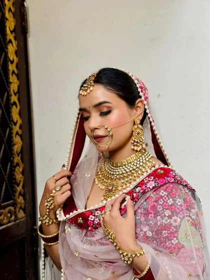 A bride looking serene and beautiful in a floral print sabyasachi-style lehenga. The traditional jewellery, including the nath and maang tikka, completes the look.