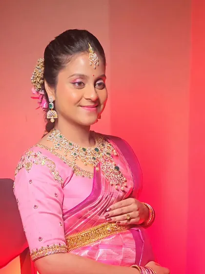 Chandralekha looking radiant against a warm pink backdrop for her Seemantha.