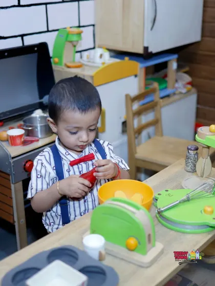 Even the tiniest guests have a world of their own to explore. This little chef is busy in our pretend play kitchen, a corner designed for imaginative fun for toddlers and young children.