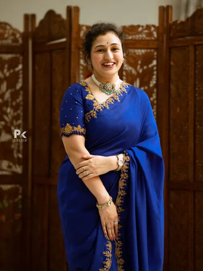 A smiling portrait of Pragathi Shetty in the royal blue saree, looking effortlessly elegant.