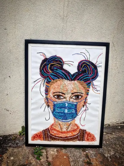 The completed and framed thread art piece, ready to be hung. The black frame provides a strong contrast to the colourful artwork.