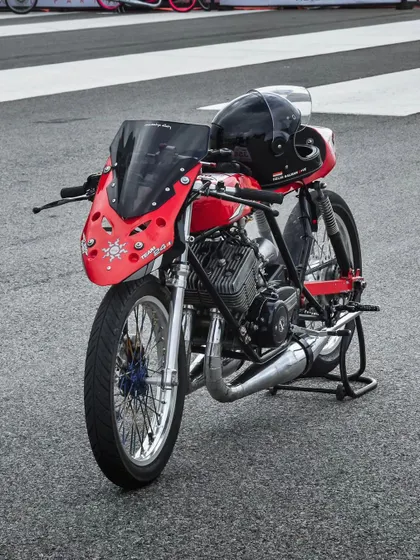 A custom red drag bike with its helmet resting on the seat, a moment of quiet before the storm.