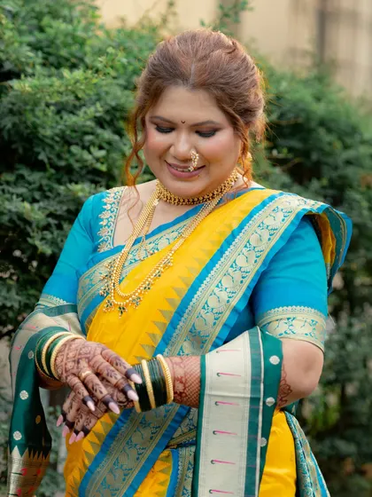 A classic bridal portrait. The bride looks elegant in her yellow and blue Nauvari, with traditional gold jewelry and a soft, romantic hairstyle.