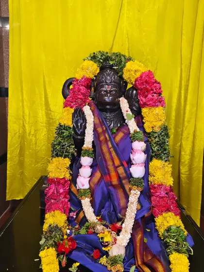 The idol of Lord Anjaneya is decorated with a silk cloth and vibrant flower garlands for a temple festival.