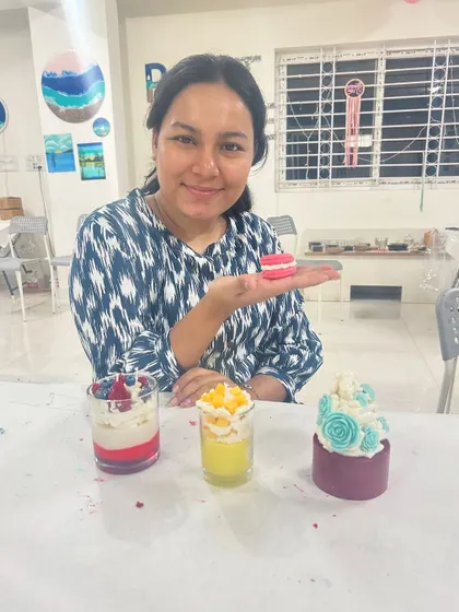 A guest showing off her perfectly crafted dessert candle, complete with a tiny macaron on top.