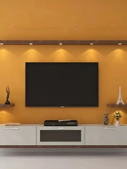 A simple yet elegant floating TV console in white and wood. The unit is mounted on a bold yellow wall, with overhead spotlights and small decorative shelves on either side.