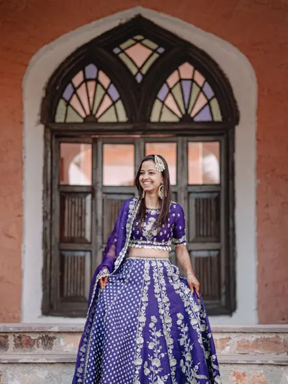 A joyful portrait of the bride in front of a vintage window, her smile radiating happiness during her Mehendi ceremony.