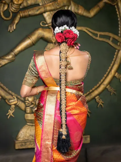 A stunning view of a bride's hair, adorned with fresh red roses and a full-length antique gold jada.