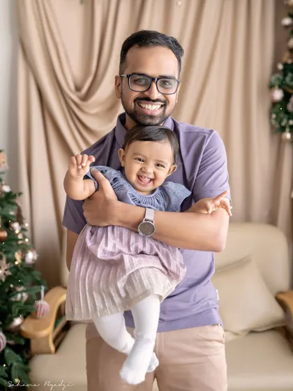 A father holds his daughter, who is sticking her tongue out playfully. This fun and silly moment is a perfect capture of her budding personality.