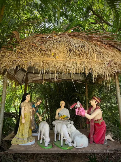 A diorama showing a scene from a story, with figures gathered around a central character under a thatched roof.