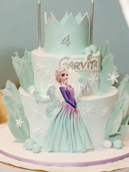 A beautiful two-tiered cake for a 'Frozen' themed party, featuring an edible image of Elsa and delicate, ice-like sugar decorations. The cake is a centerpiece that perfectly matches the event's decor.