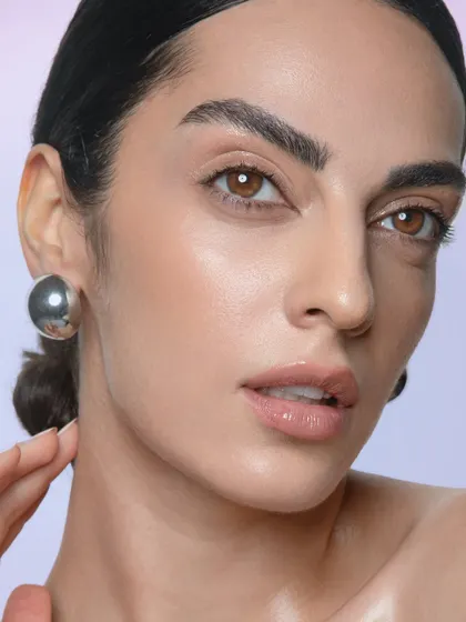 A classic beauty portrait. The makeup is clean and simple, with an emphasis on glowing skin and a natural, glossy lip.