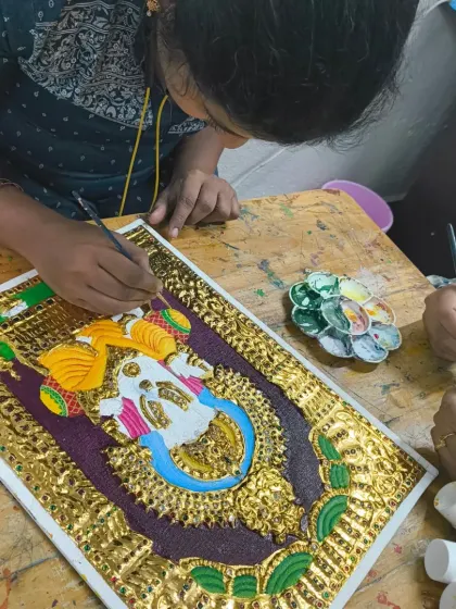 I'm helping a student with the delicate brushwork on her Tanjore piece. This art form requires patience and precision, and I'm here to guide you through every detail.