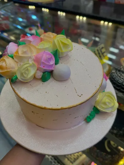 A lovely cake decorated with a bouquet of pastel-colored buttercream flowers. The soft colors and delicate piping create a beautiful and artistic design.