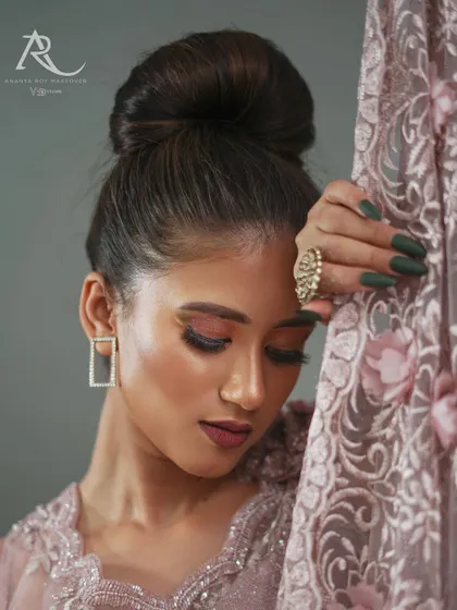 This close-up portrait focuses on the mood of the collection. It highlights the makeup, the elegant updo, and the texture of the embroidered fabric, creating an image that is both a beauty shot and a detailed garment feature.