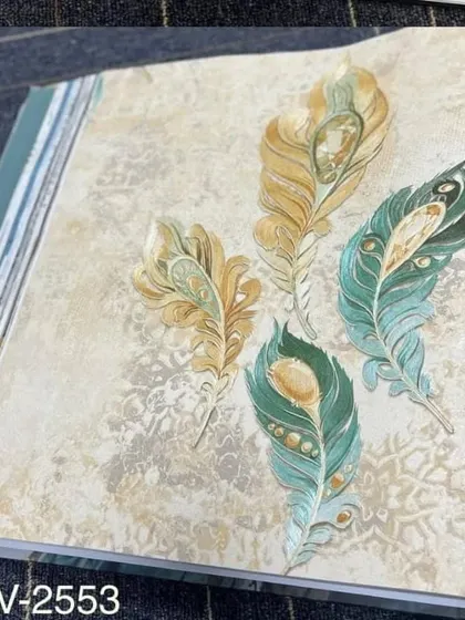 A sample from a wallpaper book showing a design of scattered peacock feathers in shades of green and gold.