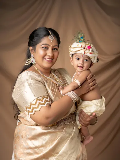 A mother and her two sons, all dressed in beautiful matching golden outfits for their Kannaiah-themed family photoshoot. A perfect portrait of love and togetherness.