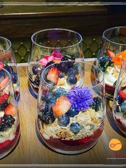 Individual berry and granola parfaits served in elegant glasses. This is a stylish and convenient way to serve dessert at a buffet, ensuring consistent portions and beautiful presentation.