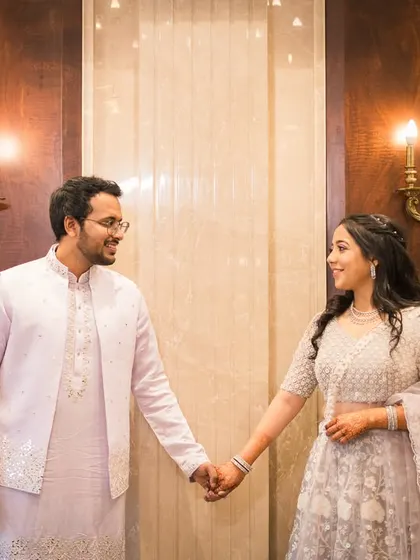 Holding hands in a beautifully lit, elegant indoor space. This shot combines architectural beauty with a simple, romantic gesture.