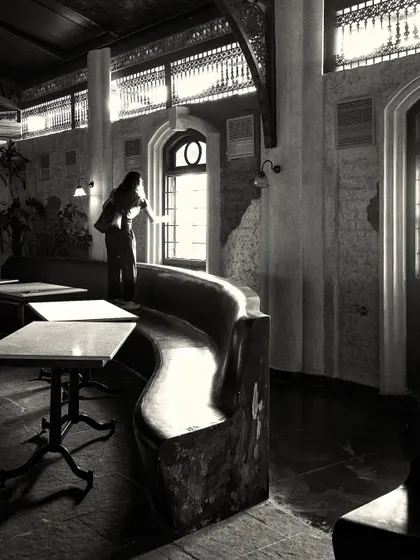 A quiet moment captured in the space, showing a person by the window. The design incorporates natural light to create an inviting daytime atmosphere.