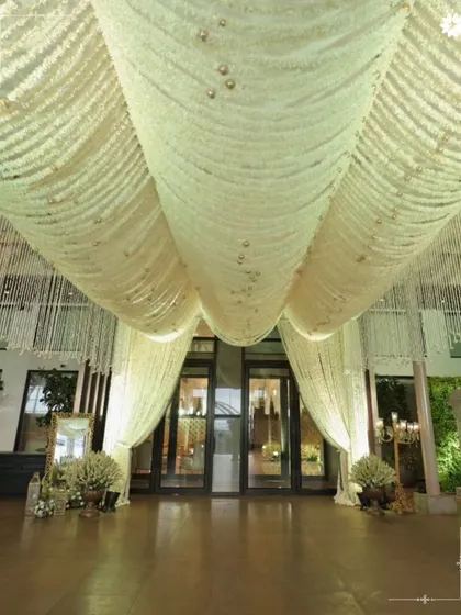 The grand entrance to the ballroom, draped in flowing white fabric. This creates a dramatic sense of arrival and sets a tone of ethereal elegance for the celebration within.