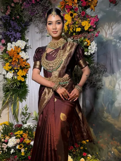 A deep wine-colored Kanchivaram saree creates a royal and elegant South Indian bridal look. The puff-sleeved blouse and temple jewellery complete this stunning ensemble.